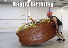 a man carrying a giant piece of cake with candles on it