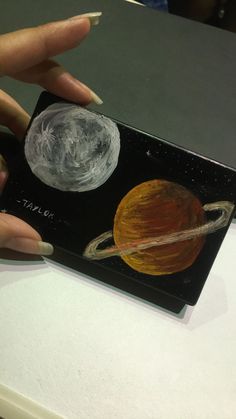 a woman's hand is holding a miniature model of the solar system