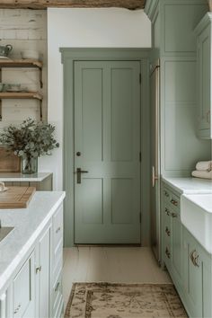 a kitchen with green cabinets and white counter tops, along with a rug on the floor