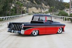 an old black and red truck parked on the side of a road