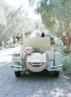 the bride and groom are riding in an old fashioned car decorated with floral wreaths