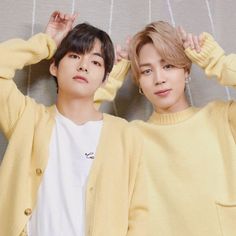 two people standing next to each other with their hands on their head and wearing yellow sweaters