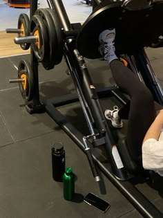 a woman sitting on top of a bench next to a barbell exercise machine with two green bottles