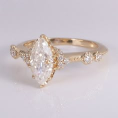 a gold ring with a pear shaped diamond surrounded by small round brilliant cut white diamonds