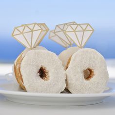 three donuts with white frosting and diamond decorations on them sitting on a plate