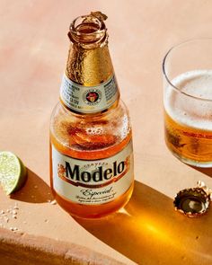 a close up of a bottle of beer next to a glass with a lime on it