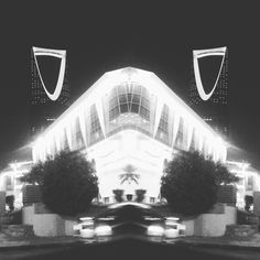 a black and white photo of a building with cars parked in front of it at night