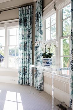 a vase with flowers sitting on top of a glass table in front of a window