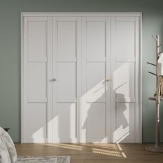 a bedroom with green walls, white closets and a rug on the wooden floor