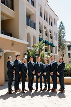 a group of men standing next to each other in front of a tall white building