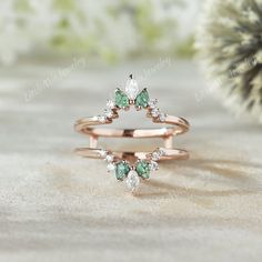 two rings with green and white stones on them sitting on a table next to a cactus