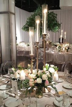 a table set up for a formal dinner with candles and flowers on the centerpiece