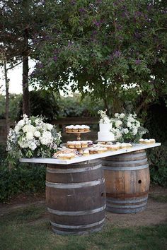 two wooden barrels with cakes on top and flowers in the middle, sitting next to each other