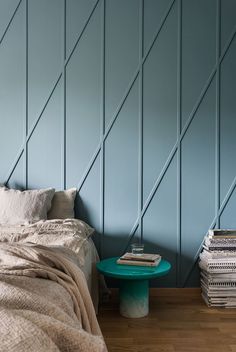 a bed sitting next to a stack of books on top of a wooden floor