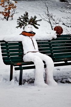 a snowman sitting on top of a park bench