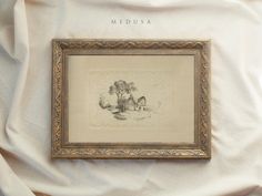 a framed drawing on a white sheet with the word medusa written in gold frame