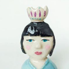 a ceramic figurine with a crown on top of it's head, against a white background