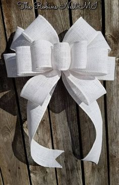 a large white bow hanging on the side of a wooden fence with words above it