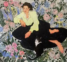 a woman sitting on the ground next to a black and white cat in front of flowers