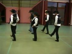 four young men in black and white outfits are dancing on the dance floor with their backs turned