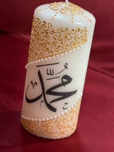 a white candle with arabic writing on it