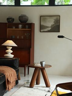 a living room filled with furniture and a lamp on top of a wooden table next to a window