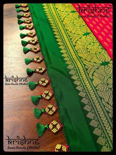 green and red saree with tassels on the border, sitting on a wooden table