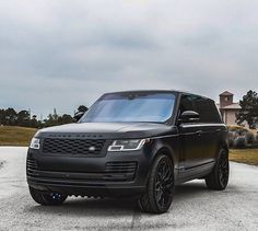 a black range rover parked on the side of a road in front of a house