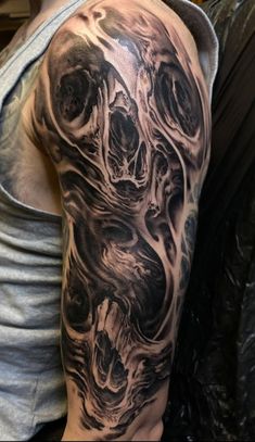 a man's arm covered in black and grey ink with an abstract design on it