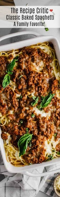 a casserole dish filled with meat and cheese on top of a white table cloth