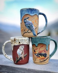 three coffee mugs with birds painted on them