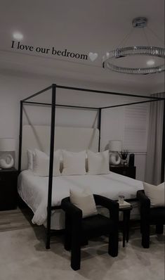 a white bed sitting in a bedroom next to a black table and chair on top of a hard wood floor