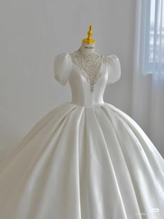 a white ball gown with a gold crown on the neckline and beaded shoulders