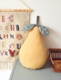 a pear sitting on top of a table next to a wall hanging with alphabets