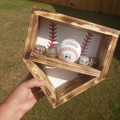 a hand holding a baseball in a wooden box