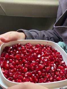 a person holding a white bowl filled with pomegranate