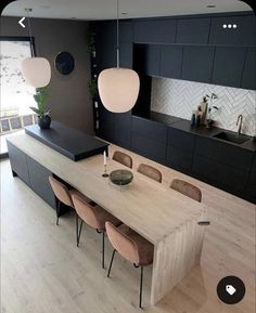 a modern kitchen with an island and dining table surrounded by chairs in front of the counter