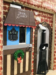 the train station is made out of cardboard and has a wreath on it's door