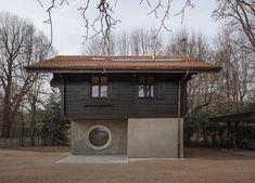 a house with a washing machine in front of it and lots of trees behind it