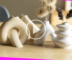 three white vases sitting on top of a wooden table