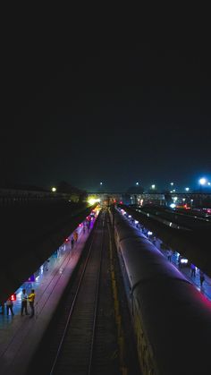 people are standing on the train tracks at night