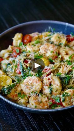 a pan filled with shrimp and vegetables on top of a wooden table