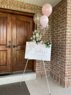 a sign with balloons and flowers on it in front of a door