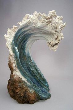 a sculpture of a wave on top of a rock with blue and white waves coming out of it