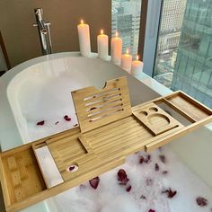 a bathtub with candles and soap in the tub, next to it is a wooden tray