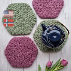 three crocheted coasters with flags on them and a teapot in the middle