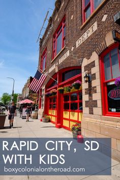 people walking down the sidewalk in front of an old brick building with red doors and windows