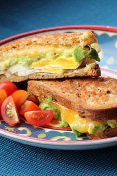 an egg and avocado sandwich with tomatoes on the side