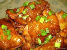 chicken wings covered in sauce and green onions