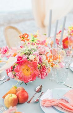 the table is set with flowers and fruit